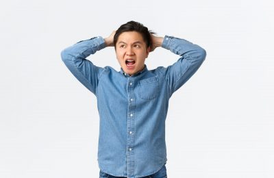 Troubled and concerned asian guy panicking, having big trouble, facing terrible situation, holding hands on head indecisive and frustrated, looking away, dont know what do, white background.